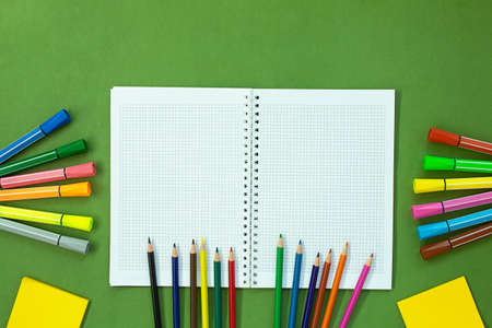 Felt tip pens, colored pencils and note for drawing. Stationery on green background. Concept back to...