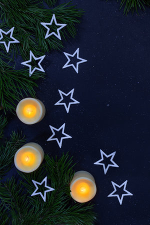 White stars, burning candles and fir branches on black background. Christmas, New Year, holiday. Night magic postcard. copy spaceの写真素材