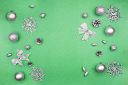 Silver Christmas decorations, balls, acorns, walnuts, bows, cones on sides on green background with place for text. New Year. copy spaceの写真素材