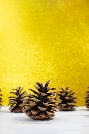 Brown fir cones on white table behind blurred yellow background. Christmas, New Year. copy spaceの写真素材