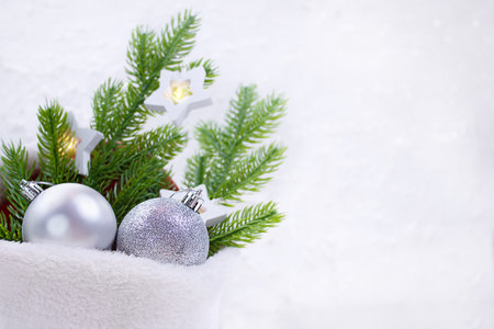 Silver shiny balls with fir branches and star lamps in fur bag on white background. Christmas, New Year. copy spaceの写真素材