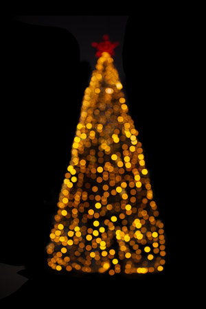 Blurred yellow Christmas tree lights on black isolated background. design element. Defocused spruce with star. overlay. New Yearの写真素材