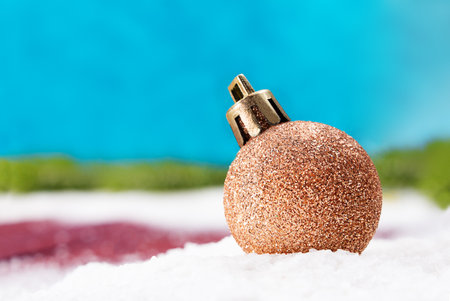 Shiny golden Christmas ball on snow, blue blurred background from behind. new year. copy spaceの写真素材