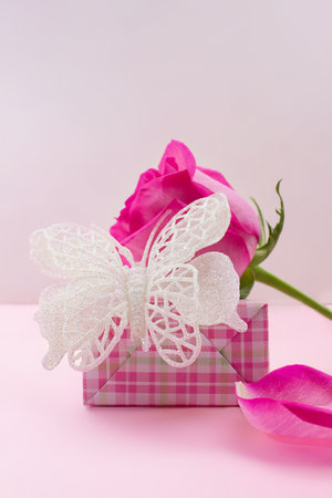Gift box with shiny butterfly, rose and petal on pink background. Birthday, March 8, Valentine's, International Women's Day. copy spaceの写真素材