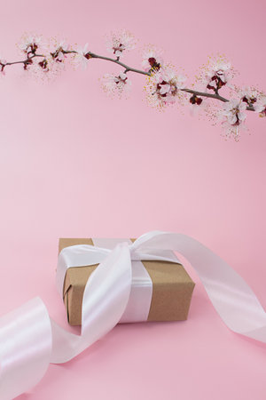 Branch of cherry, apricot, sakura with gift box with ribbon on pink background. Holidays, International women's day, Mother's day, birthday, March 8. Vertical. copy spaceの写真素材