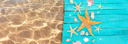 Starfish, shells on wooden blue boards of pier with clear water of sea with sand. Vacation, travel, beach. Banner. copy spaceの写真素材