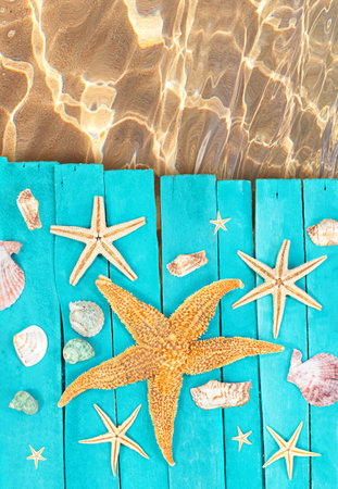 Wooden blue sea decking, boards with orange starfish, seashells near sea. Concept of vacation, tourism, summer. copy spaceの写真素材