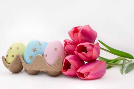 Pink tulips with colored eggs on white background. Easter. copy spaceの写真素材