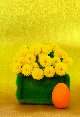 Painted eggs with grass pedestal with yellow chrysanthemums on shiny background. Easter. copy spaceの写真素材