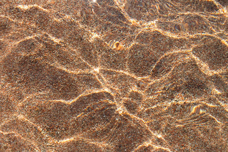 Transparent clear water sea surface texture with ripples over sandy beach with pebble. Abstract summer background. copy spaceの写真素材