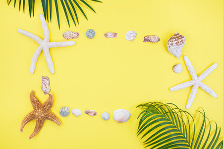 Starfish, shells in form of frame with palm tree on yellow background. vacation, travel concept. copy spaceの写真素材