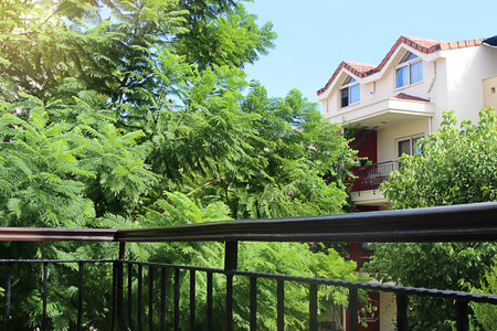 View from balcony to green trees and neighboring house with blue sky. Rest, tranquility, natureの写真素材