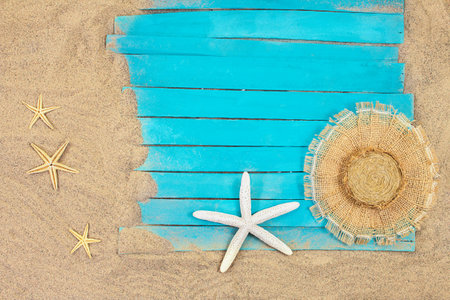 White and orange starfish with straw hat on blue rustic nautical wooden pier boards. Summer, sea background. Concept of travel, vacation. copy spaceの写真素材