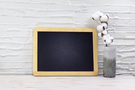 Black board for text, mock up next to vase with cotton on table. Front view empty. minimal concept. copy spaceの写真素材