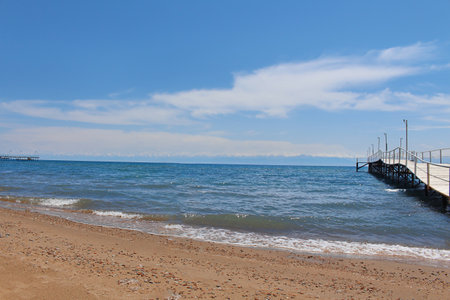 Seascape with wooden gray pier leading to sea, ocean, lake with blue sky. Travel concept, seascape, nature. Issyk-Kul, Kyrgyzstan. copy spaceの写真素材