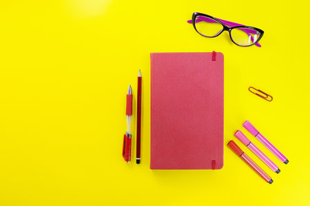 Red closed diary, notebook with pen, pencil, marker and glasses. Flat lay, back to school, learning, business, planning. copy spaceの写真素材