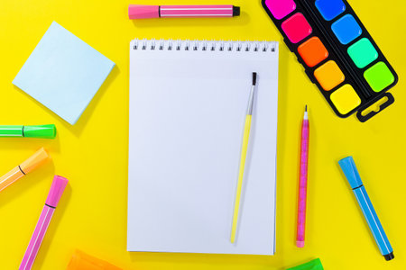 back to school drawing. Notebook checkered with brush and pencil for notes to text. Near pink, orange, green stationery. Markers, felt-tip pens, sticky note. concept of learning. copy spaceの写真素材