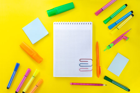 back to school drawing. Notebook checkered with pencil for notes to text with paper clips. Near pink, orange, green stationery. Markers, felt-tip pens, sticky notes, compasses. concept of learning. copy spaceの写真素材
