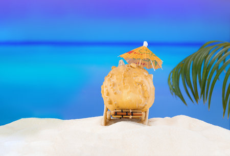 Halloween and Thanksgiving party on the beach. Pumpkin on sun lounger on sand with palm tree. Autumn season on background of ocean in hot countries. copy spaceの写真素材