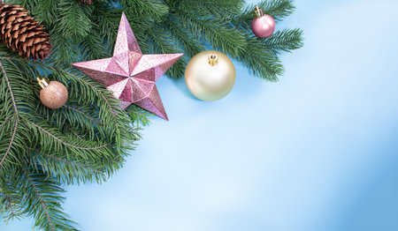 Pink shiny star, balls and cones on pine and spruce branches on blue background with place for text. Christmas, New Year. Copy spaceの写真素材