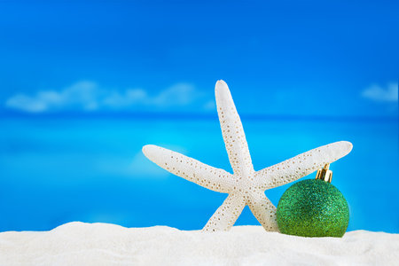 Shiny green ball with starfish on sand of beach. Christmas, New Year. Copy spaceの写真素材