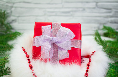 Red gift box with silver shiny bow in fur and string of beads with spruce branches. New Year, Christmas, birthday, Valentine's Day, sale. Copy spaceの写真素材