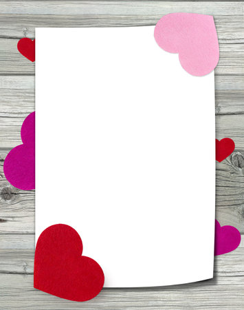 White sheet of paper with felt hearts on wooden background.の写真素材