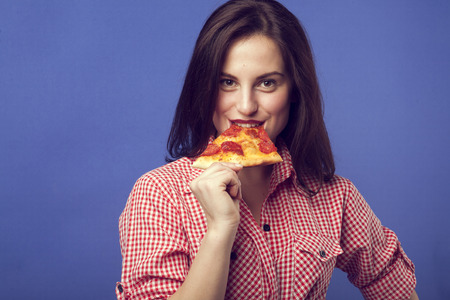 Beautiful girl eating a slide of pizzaの写真素材