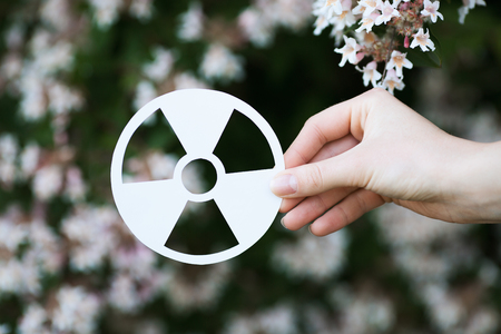 holding paper cut miniature radioactive sign over blooming treeの写真素材