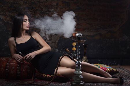 Beautiful and sexy glamorous woman smoking hookahの写真素材