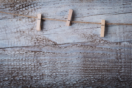 White wooden cloths pin hanging on rope over grunge wood background.の写真素材