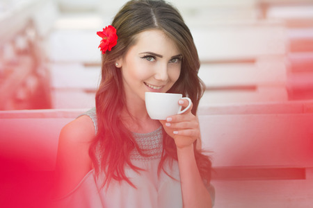 Young beautiful woman holds cup of tea in cafe.の写真素材