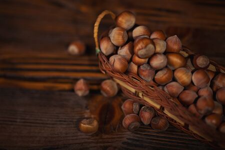 Hazelnuts in a small basket on wooden background.