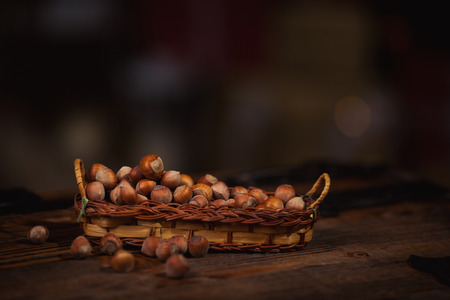 Hazelnuts in a small basket on wooden background.の写真素材
