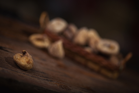 Dried figs in a small basket on wooden background.の写真素材