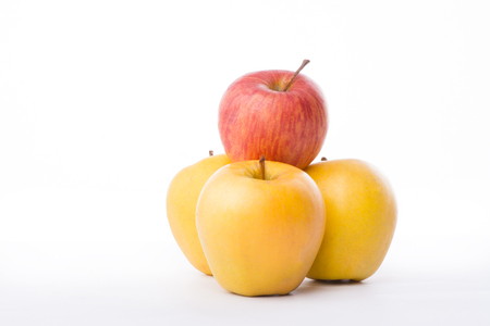 Three yellow apples and an red on white background.の写真素材
