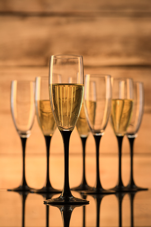 Glasses with champagne and empty wine glasses on a wooden backgroundの写真素材