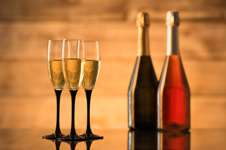 Two bottles of champagne and glasses with champagne on a wooden backgroundの写真素材