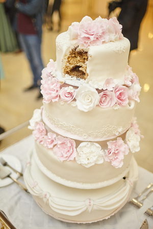 sliced three-story wedding cake decorated with flowersの写真素材