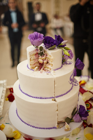 sliced three-story wedding cake with purple flowersの写真素材