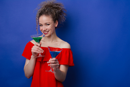 smiling girl with colorful cocktails in hands on a blue backgroundの写真素材