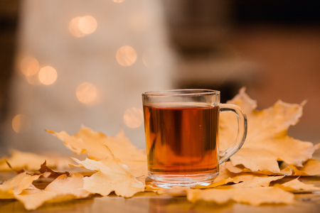 a cup of tea and yellow leaves on a wooden tableの写真素材