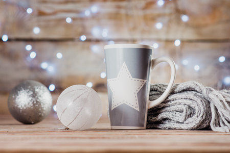 cup, Christmas toys and a gray scarf on the background of lightsの写真素材