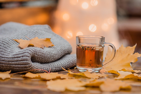 cup with tea scarf and yellow leaves against the background of lightsの写真素材