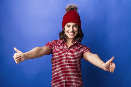 beautiful girl in a red cap smiles on a blue backgroundの写真素材