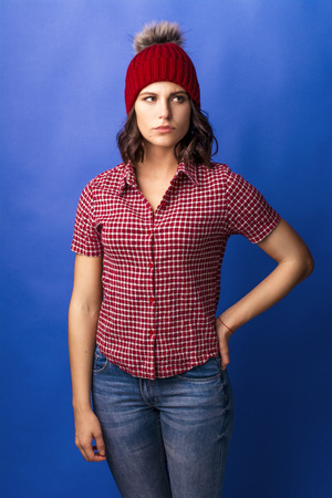 pensive girl in a red hat in the studio on a blue backgroundの写真素材