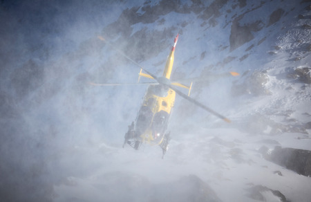 yellow helicopter on the background of snowy mountains