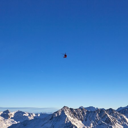red helicopter on the background of snowy mountains