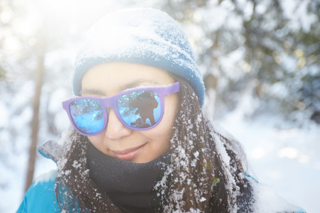 girl in glasses on the background of snowy fir trees