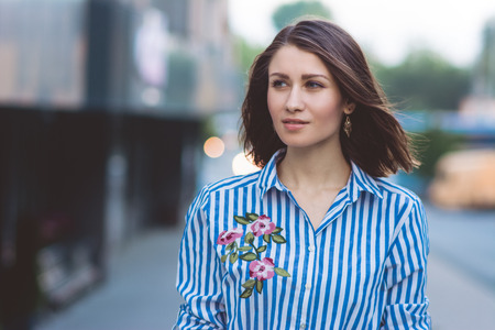 brunette girl on the street against the background of the cityの写真素材